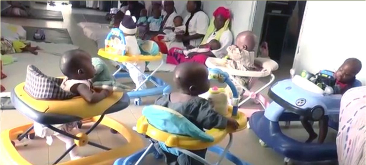 Des nourrissons dans leurs trotteurs, entourés par les berceuses de l'orphelinat